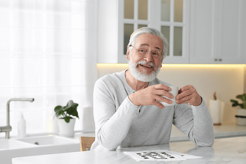 Senior man with cup of drink at table