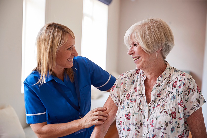 nurse-helping-senior-woman-use-walking-frame